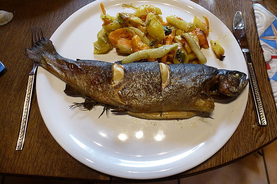 Ganzer Fisch auf Kartoffeln und Gemüse