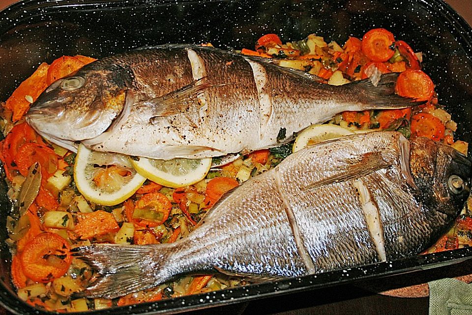 Ganzer Fisch auf Kartoffeln und Gemüse